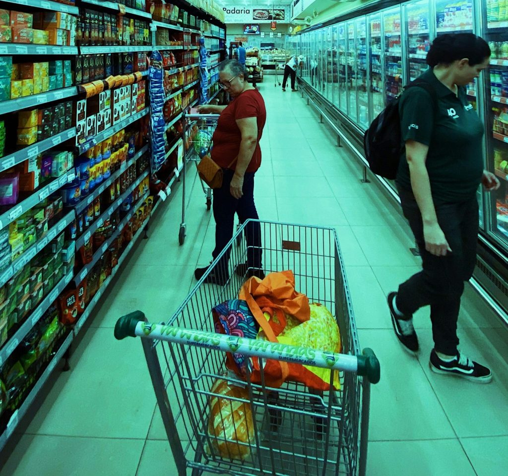 two people pushing a shopping cart in a grocery store
